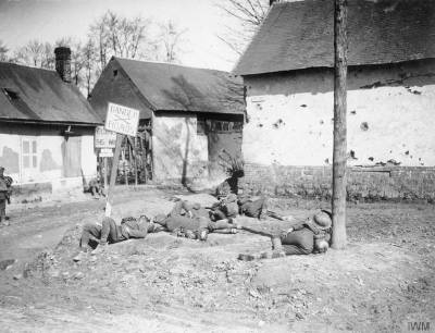 Troupes britanniques se reposant en bord de route à Forceville, en 1918 [Battle of the Lys. Exhausted British troops resting on the side of the Forceville Road.] © IWM (Q 366)